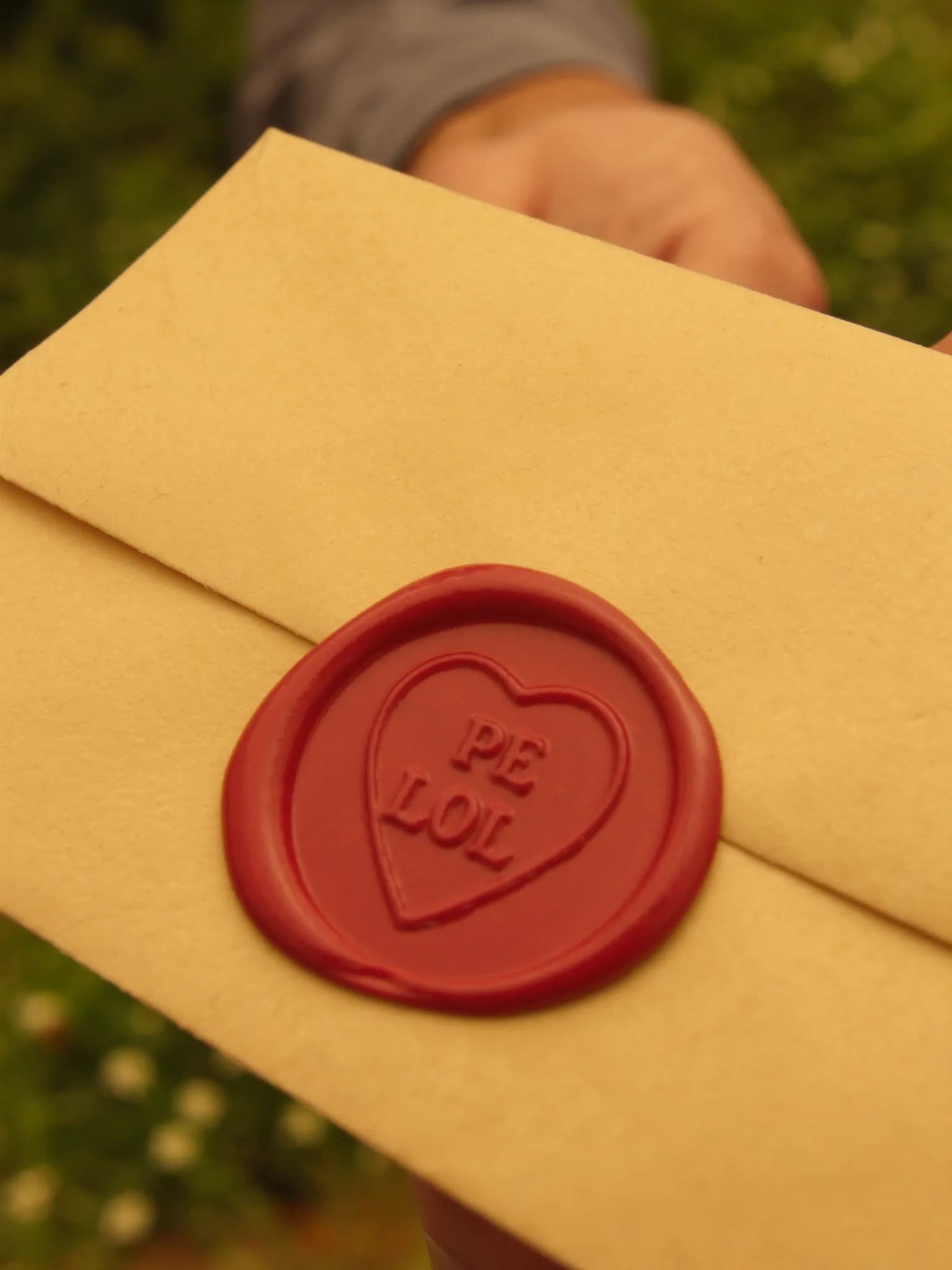 Mão entregando carta com selo dourado