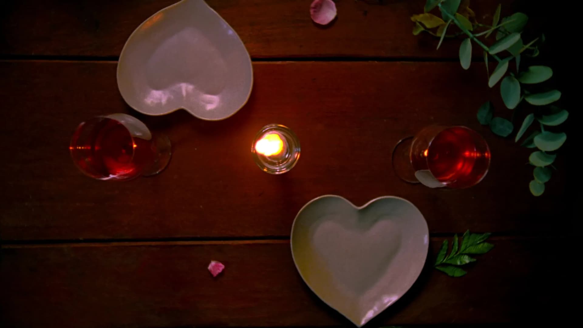 Jantar à luz de velas com taças de vinho e pétalas de rosa