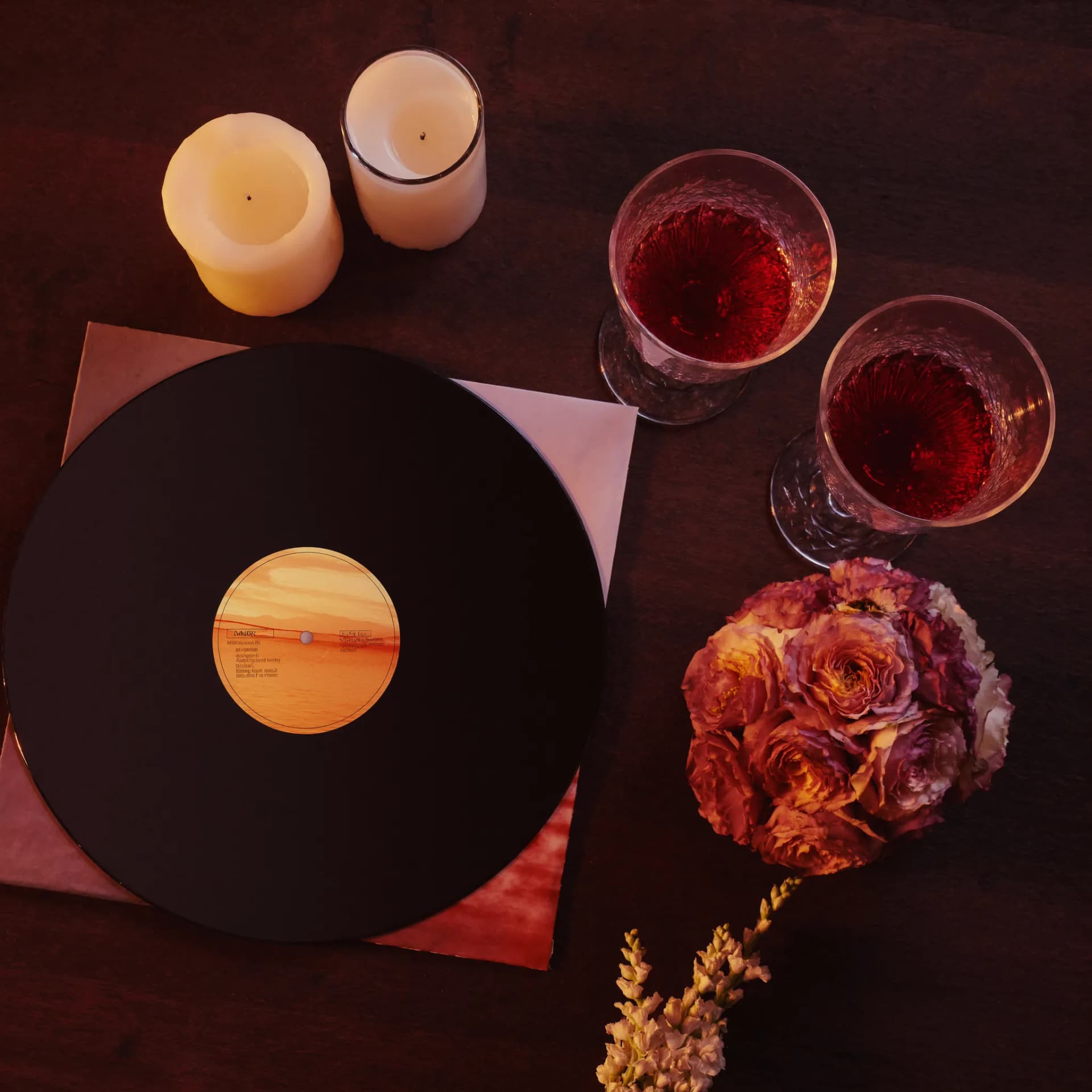 Vinil tocando ao lado de duas taças e velas acesas