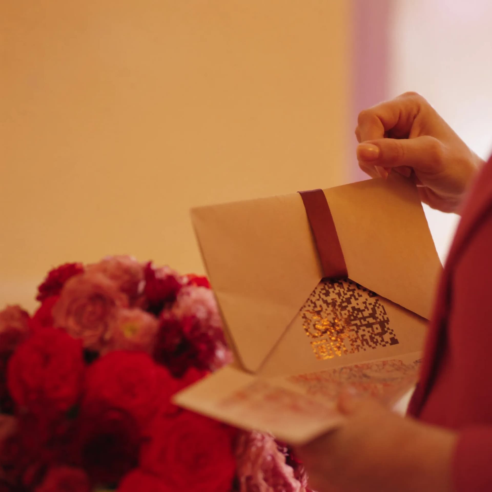Mulher abrindo carta com QR code dourado ao lado de buquê de rosas
