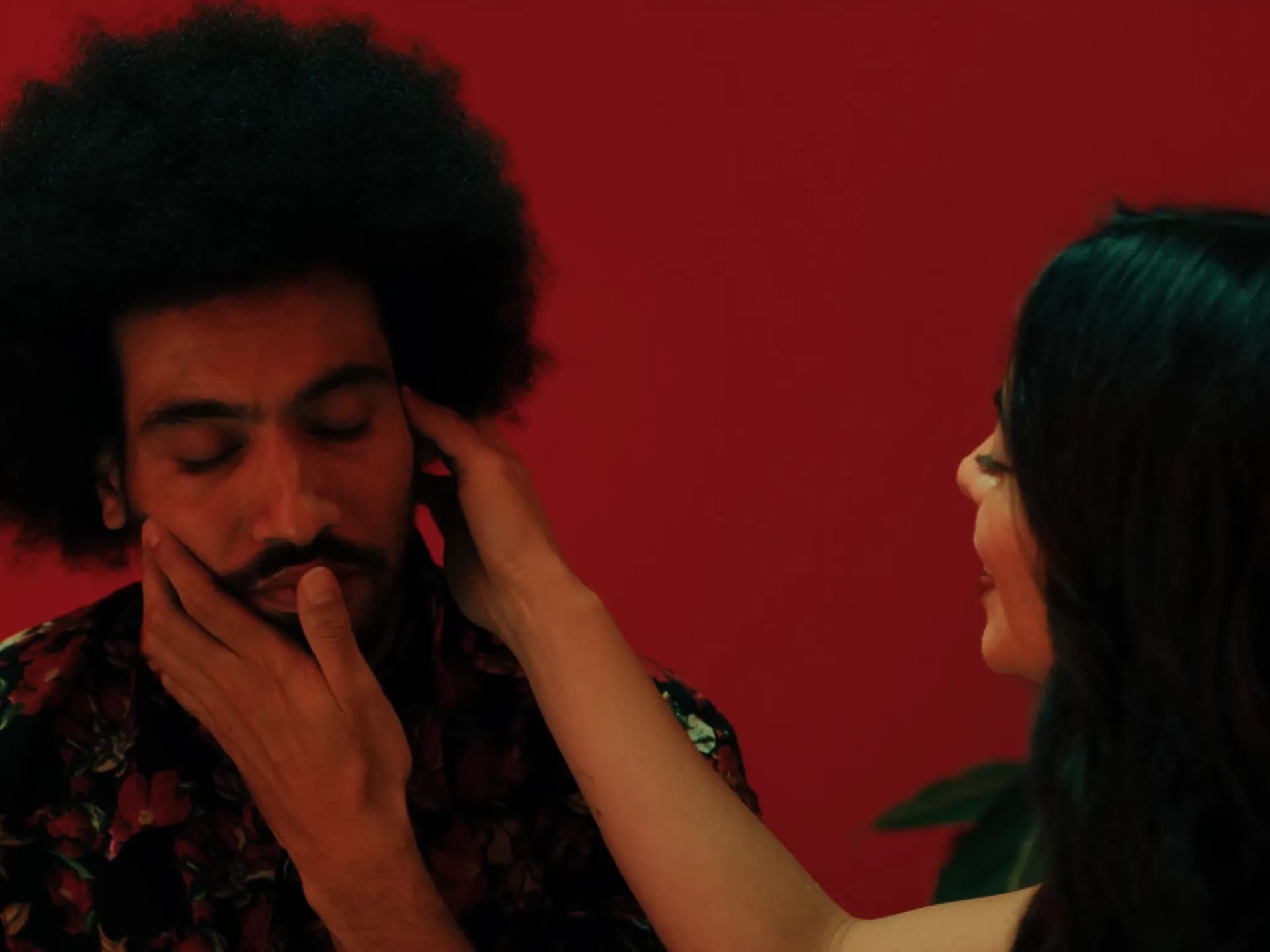 Casal afro-brasileiro se beijando ao som de música em sala iluminada por velas