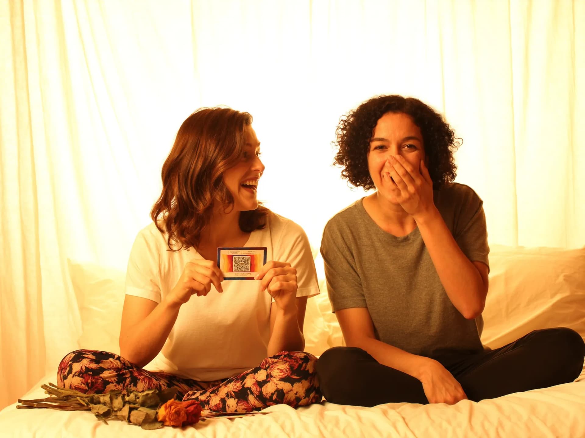 Casal LGBT segurando carta com QR code ao lado de buquê de flores